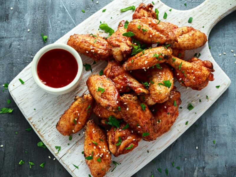 Chicken on a white plate with red sauce in a bowl