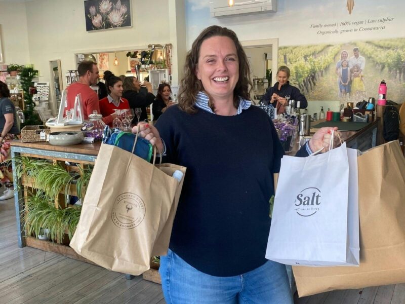 Meg is wearing jeans and has lots of bags full of goodies that she purchased at the street party.