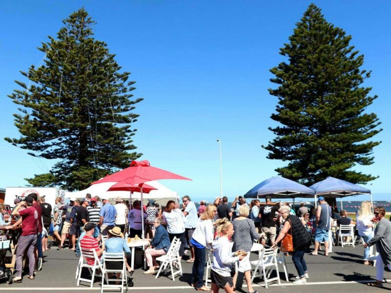 Festival crowds along Sea Parade, Port MacDonnell on a perfect day with blue sky and Norfolk Pines