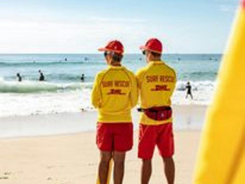 ATDW Surf Life Saving South Australia ARB Racing Carnivals.jpeg Two lifesavers with yellow tops and red shorts and caps looking out to sea