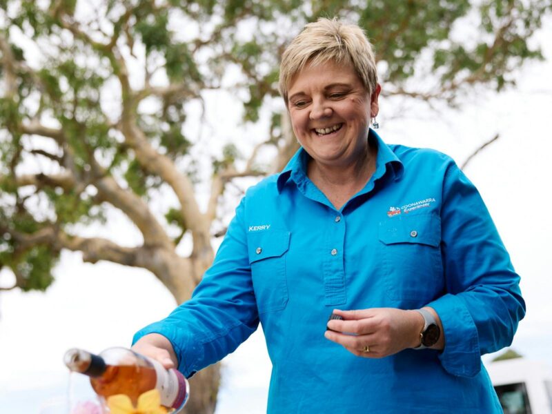 ATDW Coonawarra Experiences Touring.jpeg Coonawarra Experiences Smiling woman pouring rosé wine outdoors during a hosted experience.