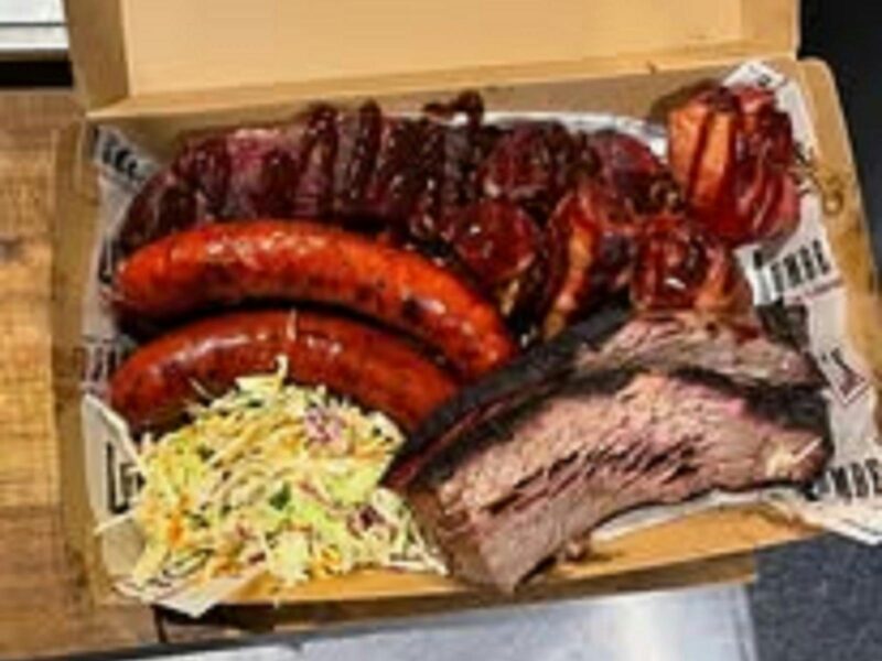 ATDW 2025 Wine And DIne.jpeg Beautiful juicy meat with a red glaze two tasty looking sausages on the left with coleslaw and chops