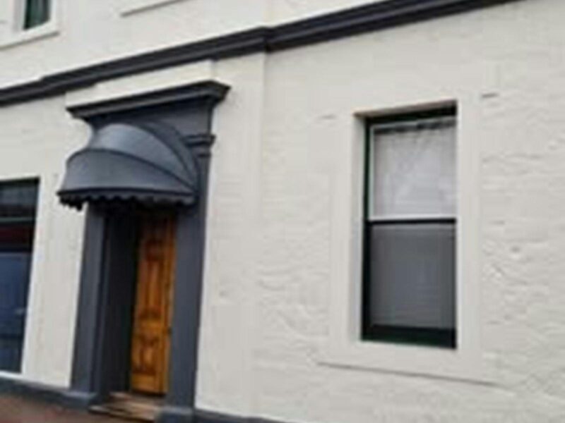 ATDW-Open-Mic-at-the-George-Hotel.jpeg A freshly painted white two storey hotel with dark grey trims and bonnet type verandah..