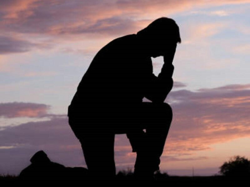 ATDW Anzac Day Glencoe.jpeg Silhoutte of a man kneeling down on one knee with his head in his hand as a symbol of remembrance