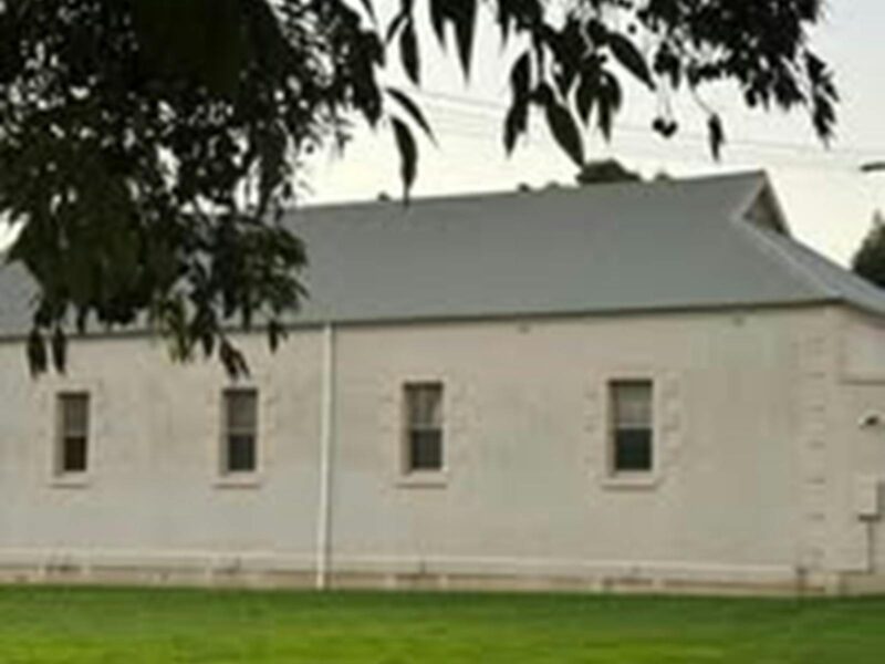 ATDW-Glencoe-Public-Hall-Connecting-Community-Dinner.jpeg Glencoe Hall is a solid, white brick building with a grey colourbond roof and green grass aroung it.