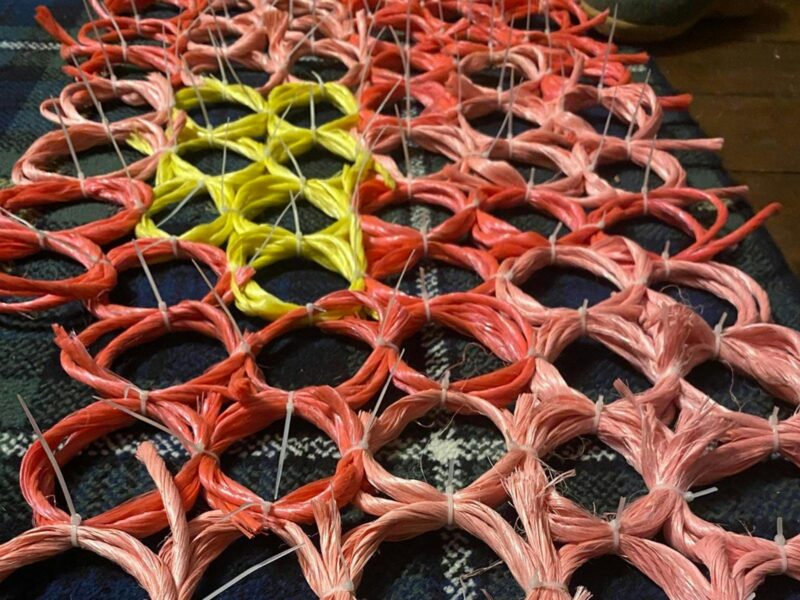 Coloured baling twine twisted into a honey comb pattern of pink, red and yellow.