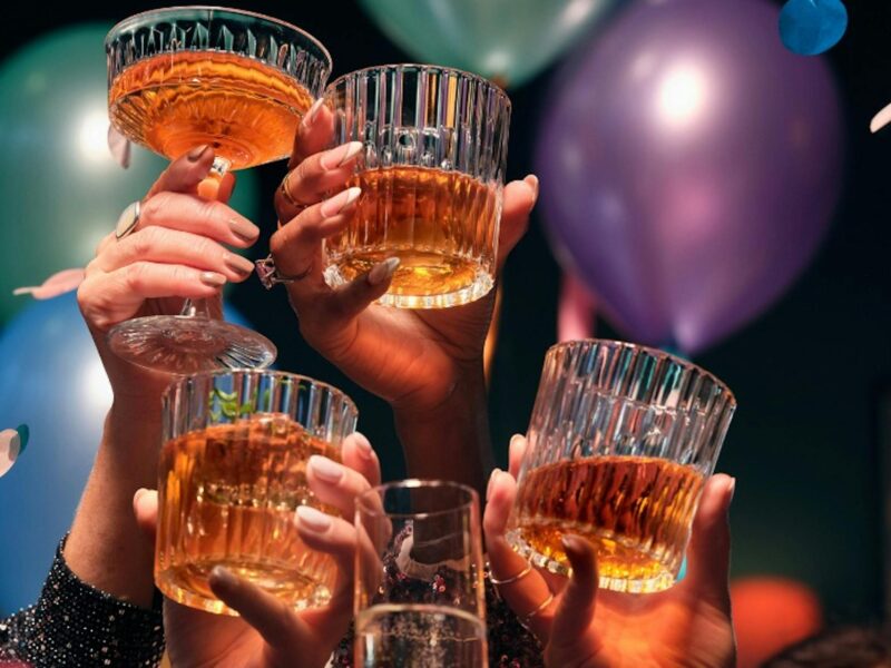 A group of people enjoying celebrating New Years Eve. They are, holding their glasses up in the air.