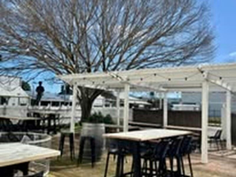 A photo of the Royal Oak Hotel's beer garden with high stools and a table and a white pergola.