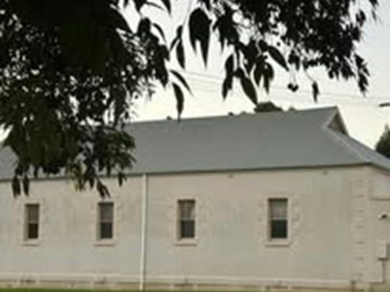 A solid stone hall with cream walls and a grey roof. There are decorative quoins on the hall.