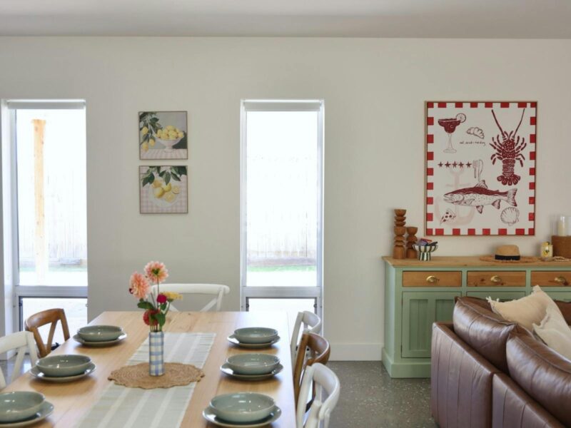 Dining table set for six beside leather sofa and artwork