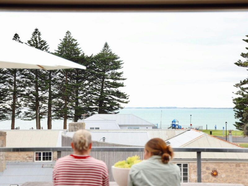Two guests seated on the balcony overlooking Robe’s foreshore and sea.