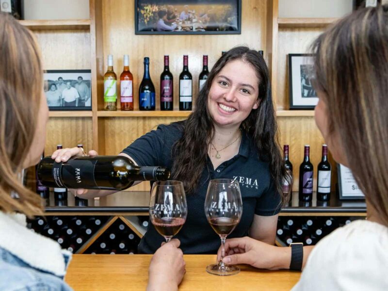 lady pours red wine at winery cellar door